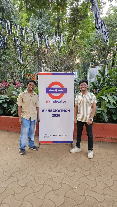 Two teammates beside the M-Indicator AI Hackathon 2026 banner
