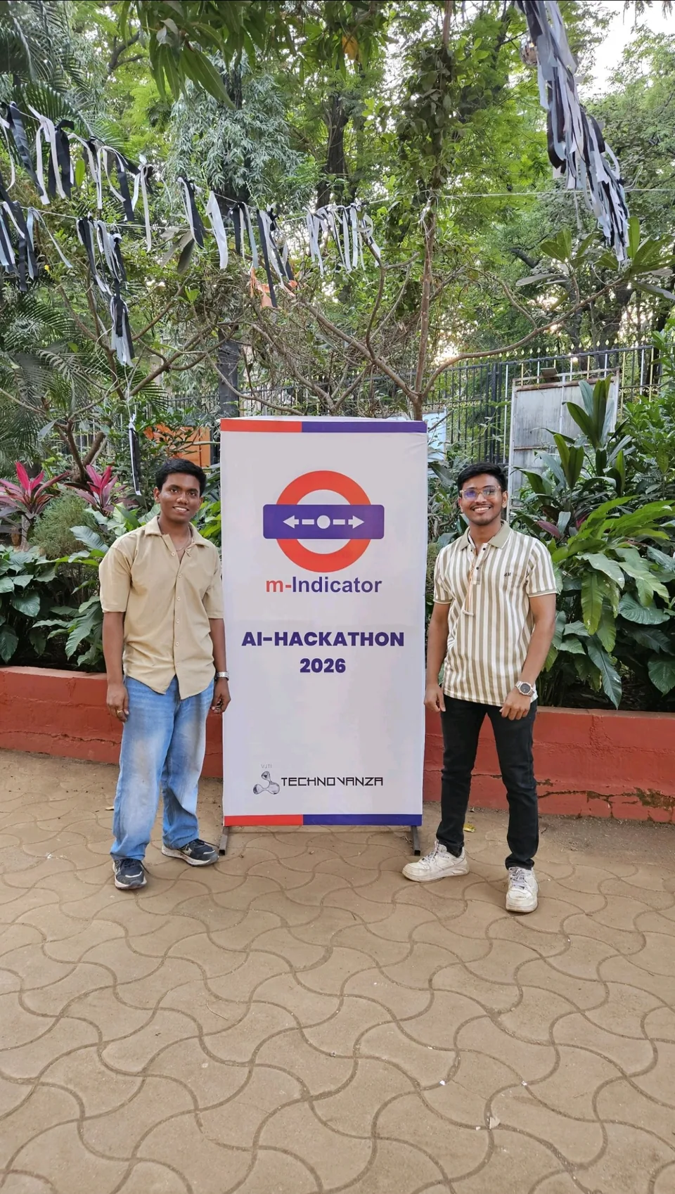 Shubham Sahu with a teammate beside the M-Indicator AI Hackathon 2026 banner