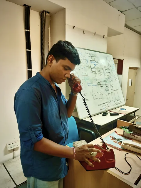 Shubham Sahu using a telephone beside electronics notes in a lab.