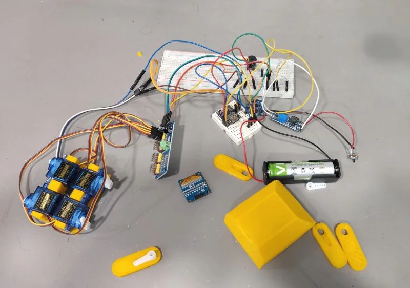 Servo motors, electronics, and yellow robot parts on the Aurigen workshop bench